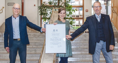 Landrat Doktor Wolfgang Buschmann hält zusammen mit Astrid Hummel und Matthias Maluck die Urkunde