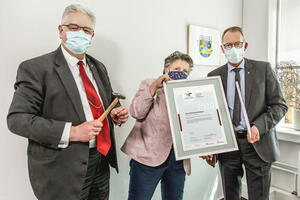 Landrat Dr. Wolfgang Buschmann freut sich gemeinsam mit der Gleichstellungsbeauftragten Petra Bargheer-Nielsen und Helmut Birkner, Fachbereichsleiter Inneres, Gesundheit und Veterinärwesen und Projekt-Verantwortlicher, über die Zertifizierung. Frau Bargheer-Nielsen hält die Urkunde in der Hand.