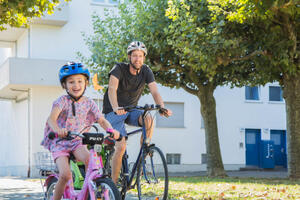 Auf dem Foto fahren ein Mann und ein Kind mit dem Fahrrad.