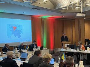 Landrat Dr. Buschmann steht am Podium und berichtet dem Kreistag über die Haushaltslage. Im Hintergrund wird eine Power-Point-Präsentation gezeigt.
