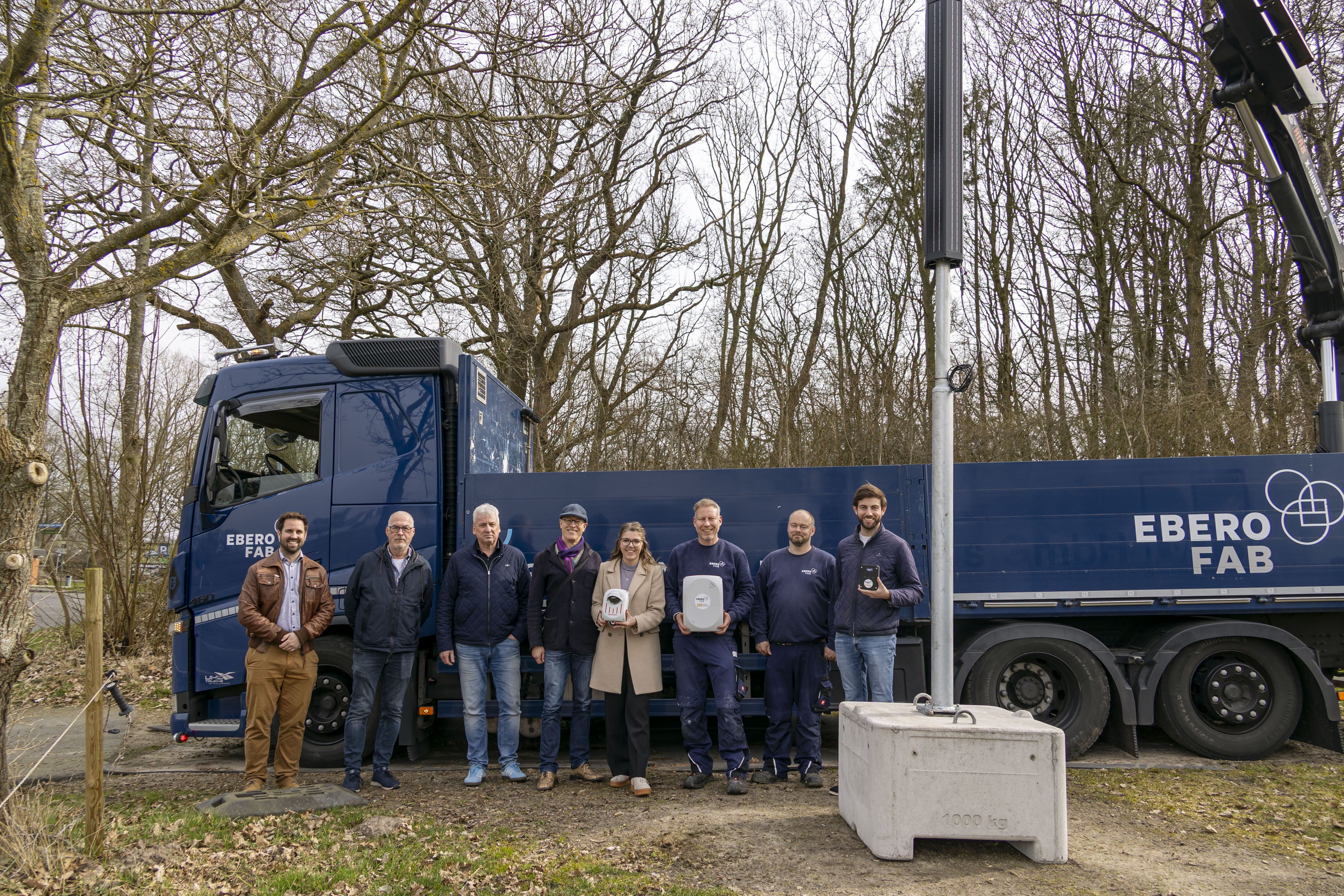 Mehrere Personen stehen vor einem blauen LKW und halten zwei Messsensoren hoch