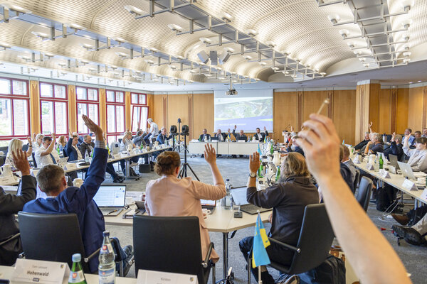 Kreistagsabgeordnete sitzen im B&uuml;rgersaal im Kreishaus in Schleswig und heben zur Abstimmung die Hand.