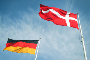 Eine deutsche und eine d&auml;nische Flagge wehen im Wind vor blauem Himmel.