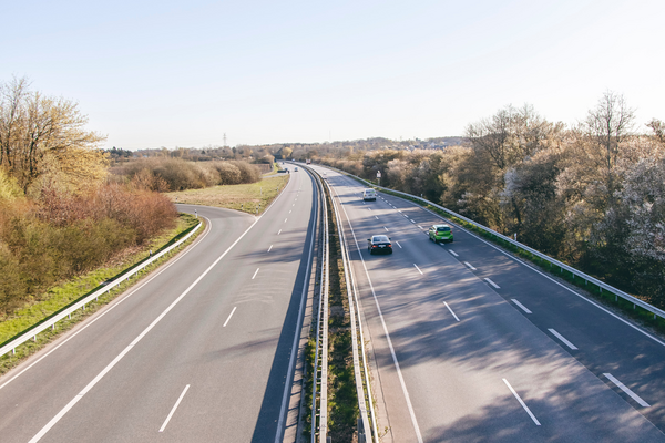 Eine vierspurige Stra&szlig;e mit ein paar Autos umringt von B&auml;umen